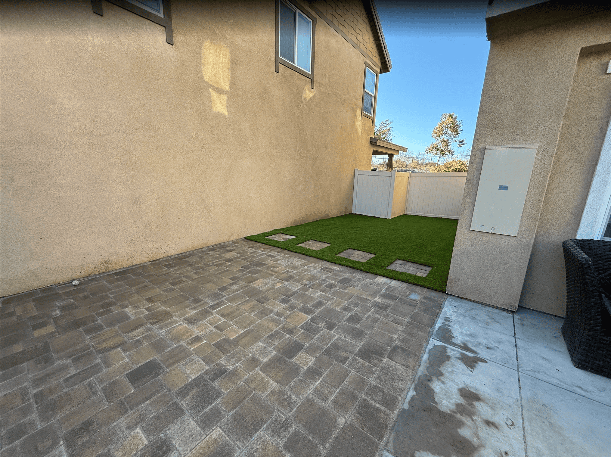 Front yard after lawn removal with new artificial turf and a paver walkway