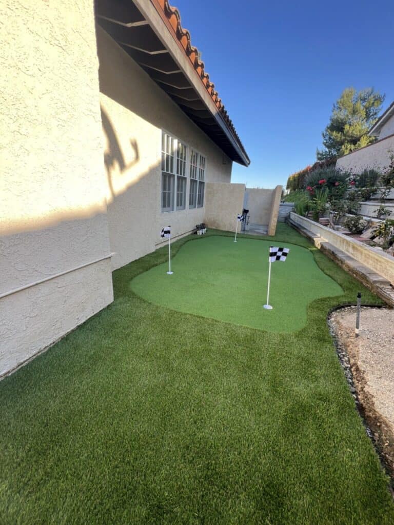 Backyard with new artificial turf and a paver patio after installation