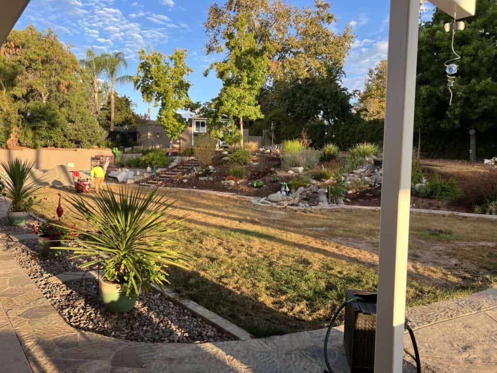 Backyard before turf installation, bare dirt and patchy grass