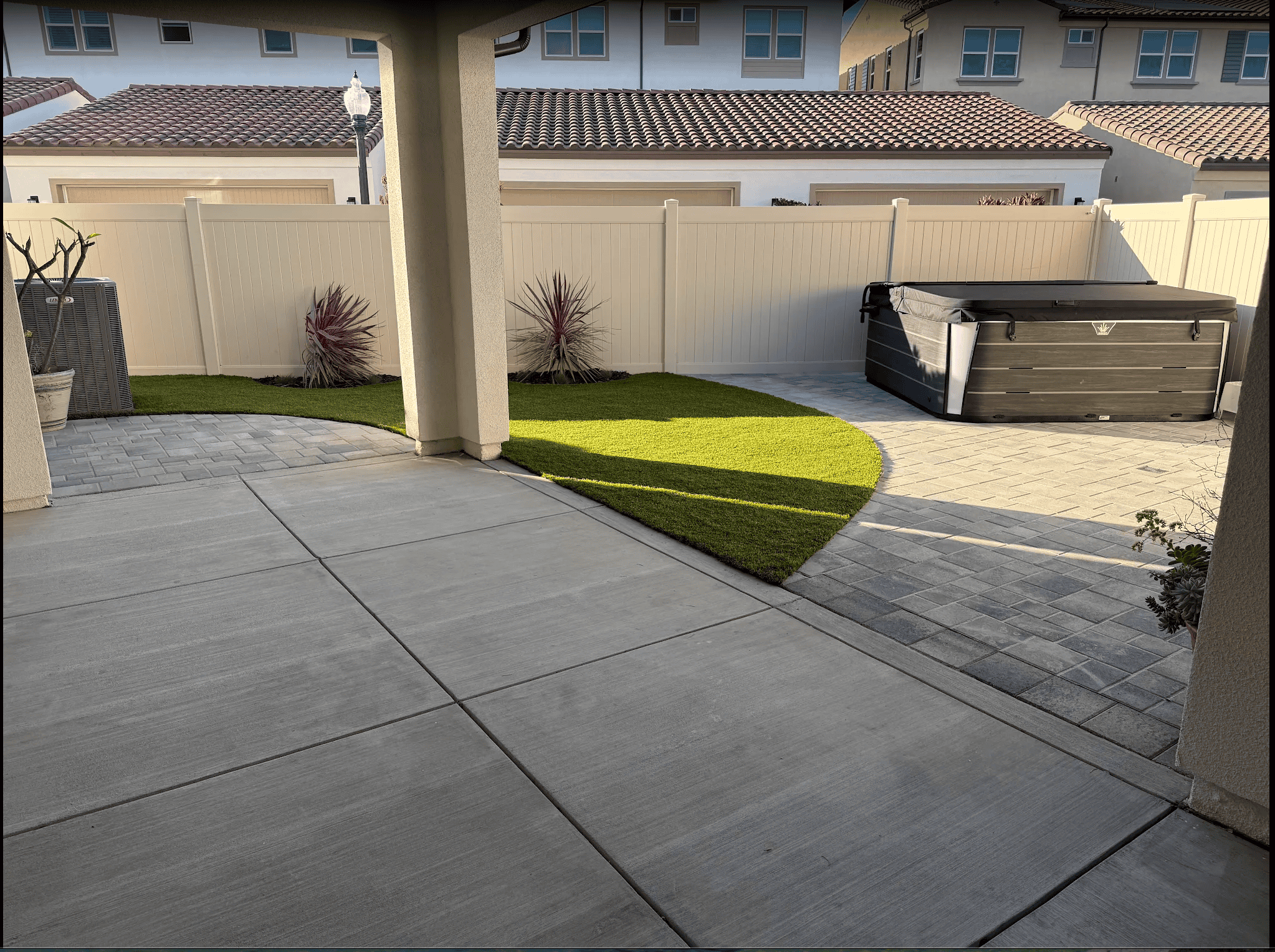 Backyard with artificial turf and a paver patio after installation by VC Turf