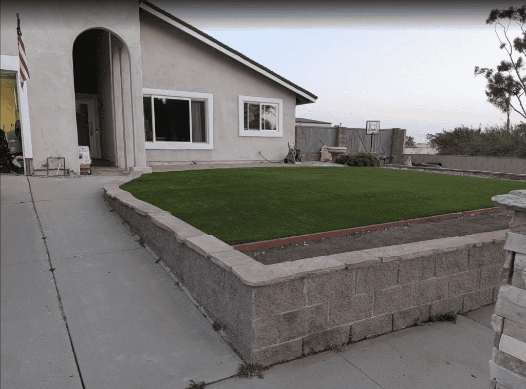 The same front yard after the remodel, with new artificial turf and pavers