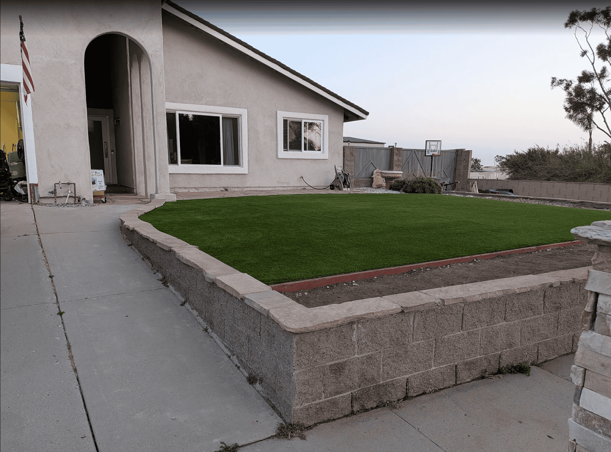 The same front yard after the remodel, with new artificial turf and pavers