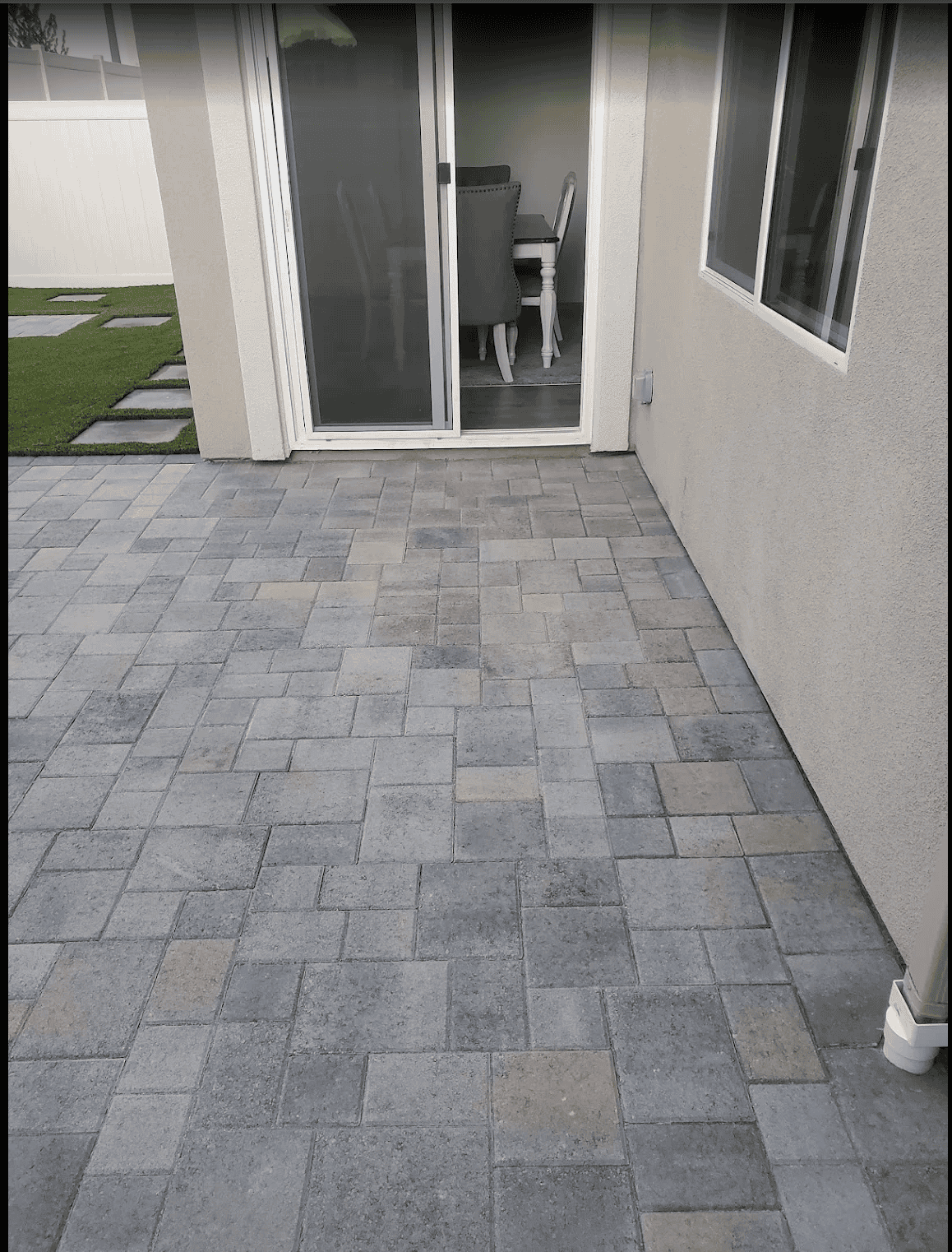 Paver driveway and walkway with a turf lawn beside them at a single-story home
